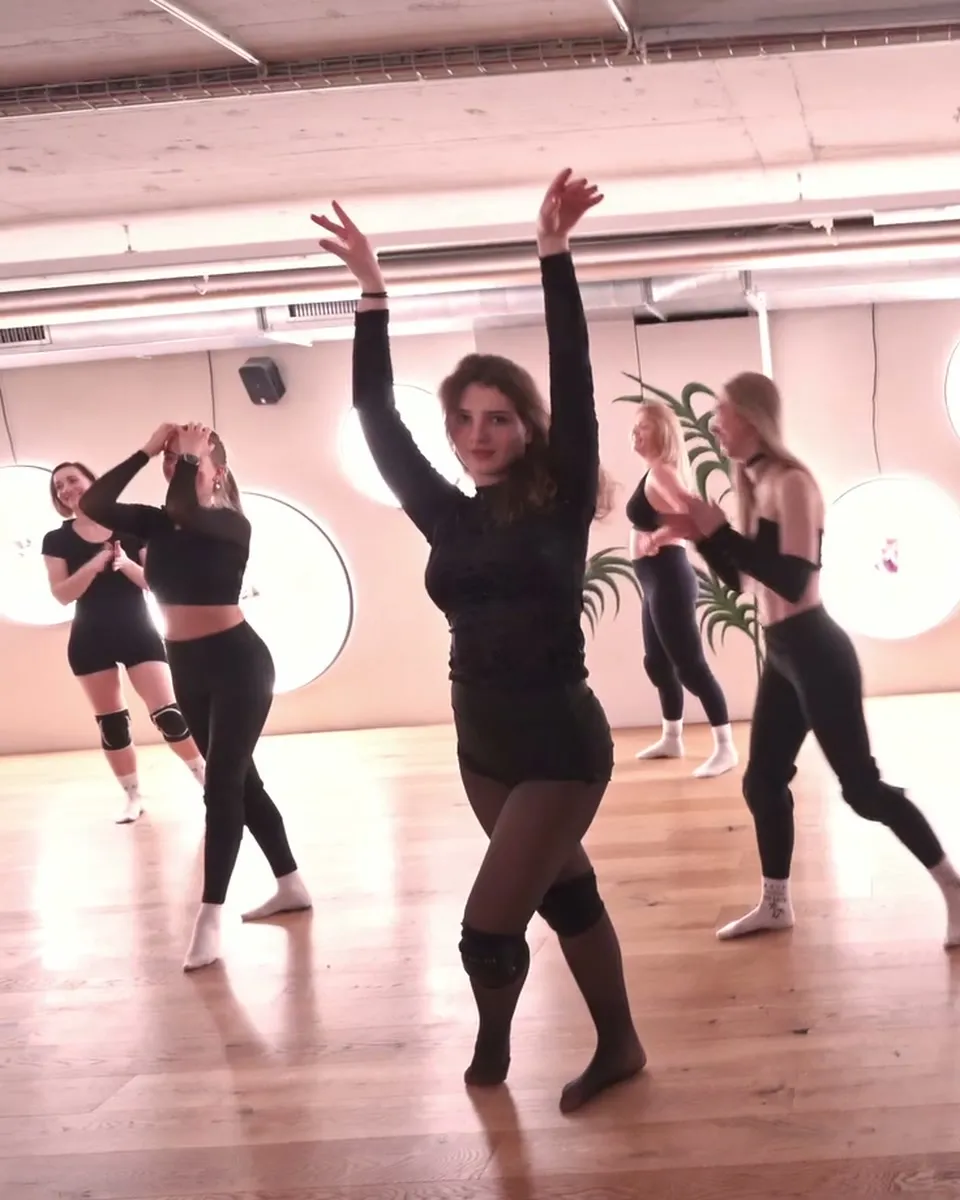 A Floorwork class in the middle of a routine, the dancer at the front reaching both arms up